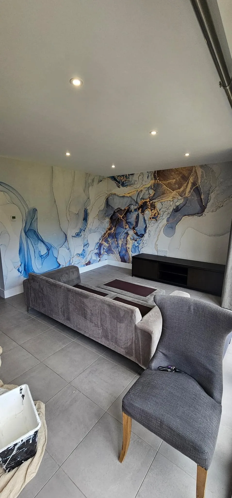 A living room with a couch a chair and a painting on the wall.