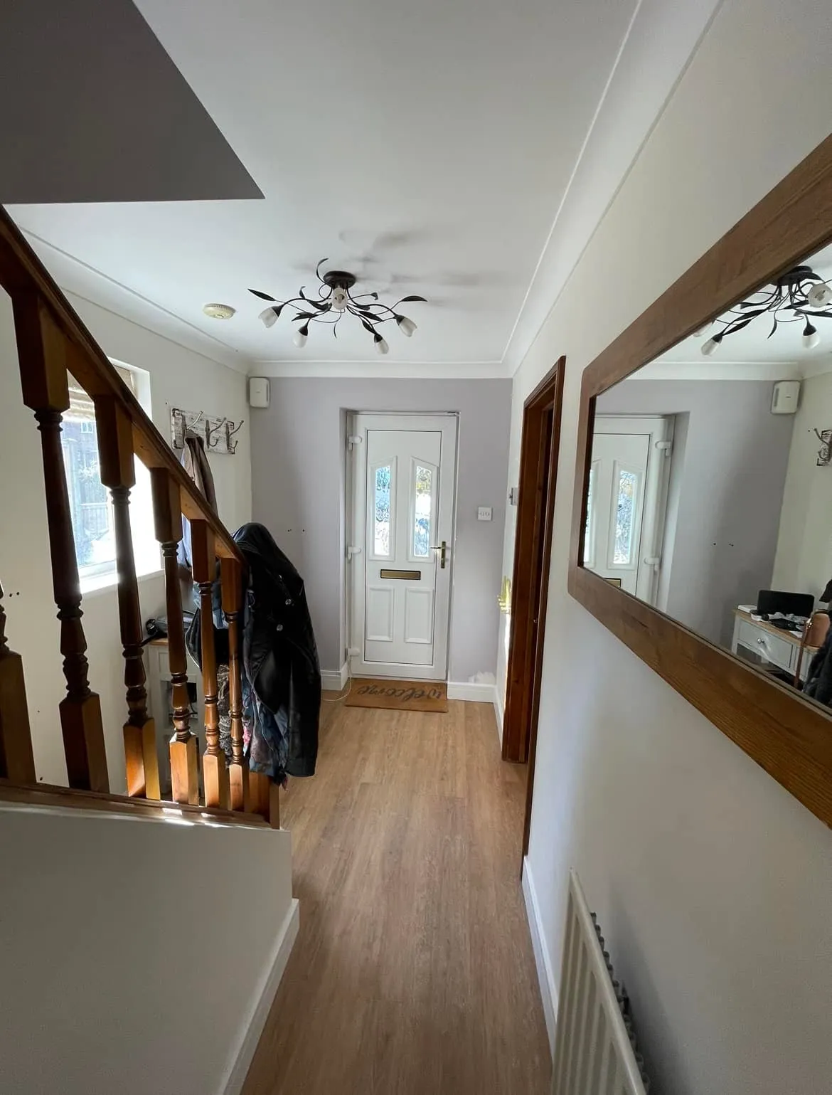 A hallway with a coat rack and a mirror.