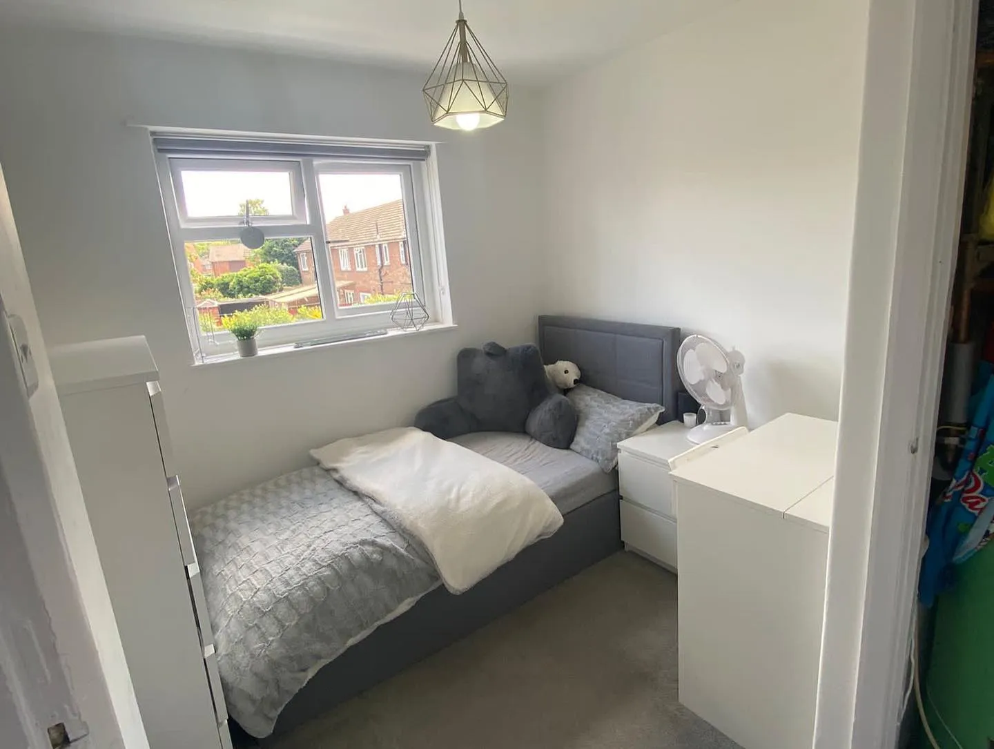 A bed room with a neatly made bed and a window.