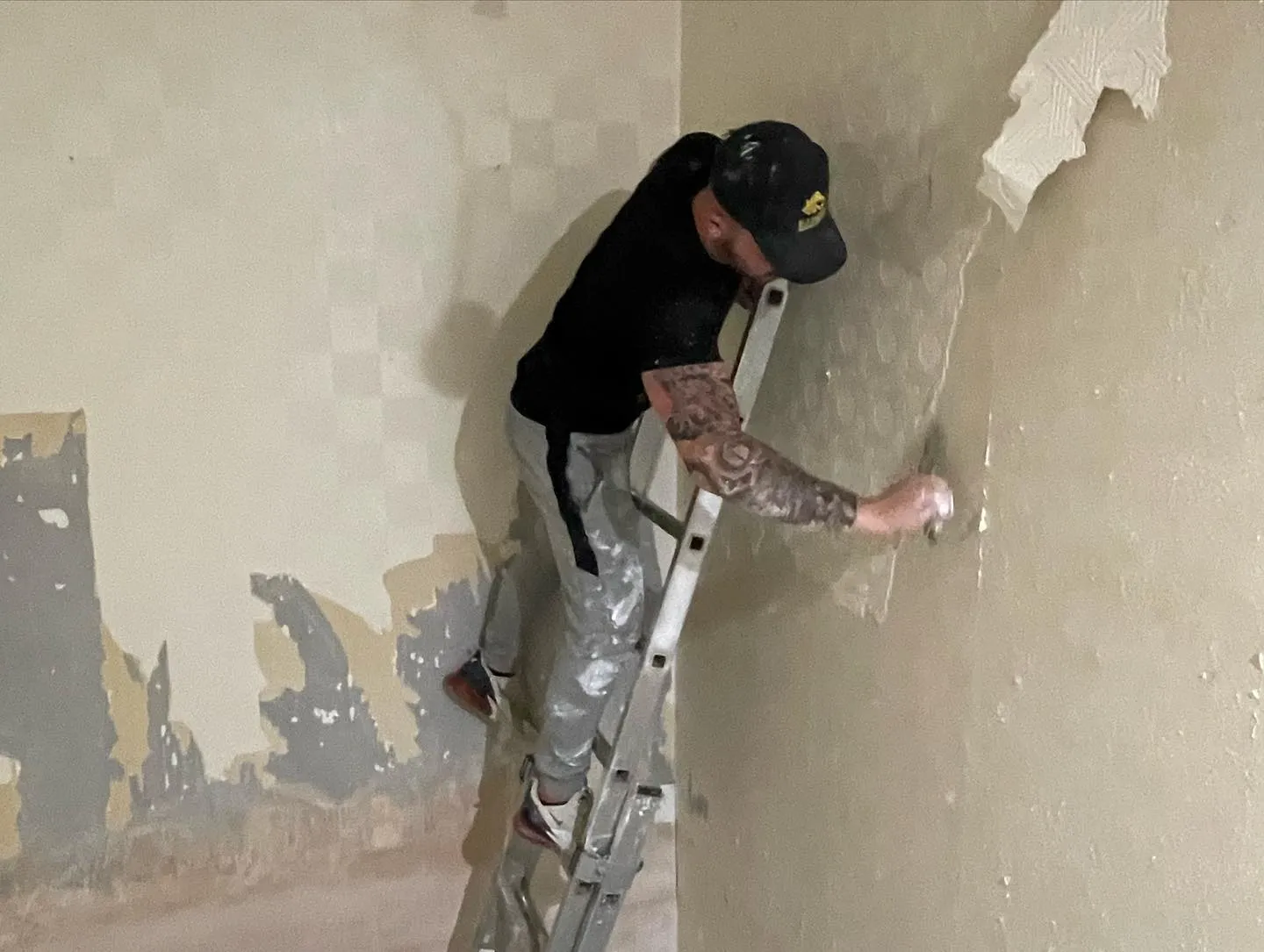 A man painting a wall with a ladder.