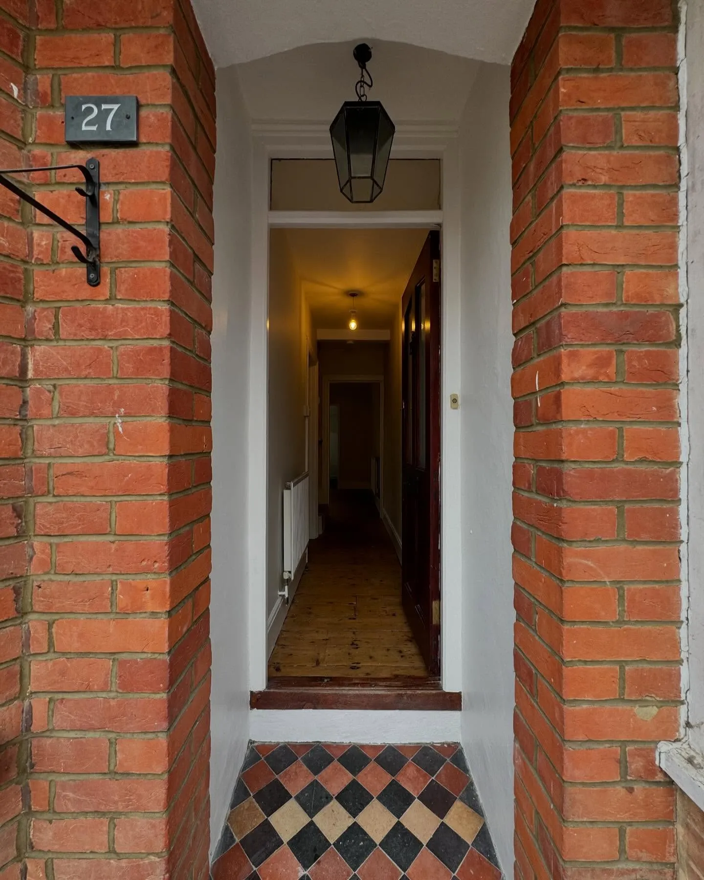 A hallway with a door and a clock on the wall.